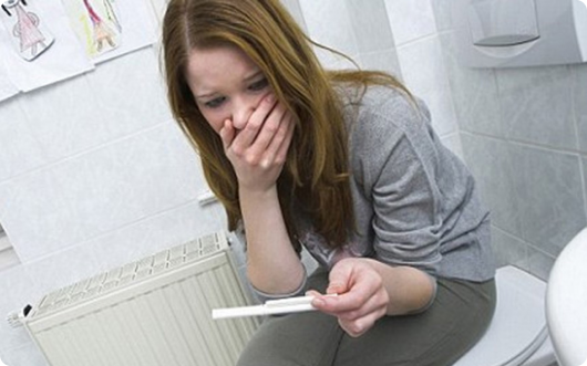 девочка подросток смотрит на тест для беременности